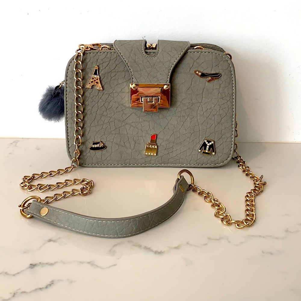 A grey purse with a gold chain.